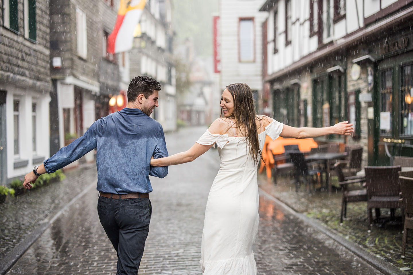 Couple dancing in the rain during their engagement shoot in Monschau, Germany